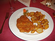 One of the typical ways of serving kotlet schabowy pork cutlet: on a plate with home fries.
