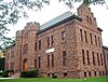 A large brown stone building with castle-like towers and a pointed roof with stepped features on the end. Hanging from its right side is a banner that says "Lake Plains YMCA".