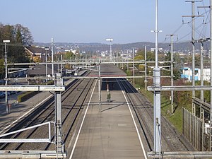 Two railway platforms covered by canopies; three railway tracks passing through