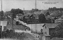 Vue prise en hauteur à proximité du tunnel avec, au premier plan, la ligne, le passage de la route de Nantes et la maison du garde barrière, à droite, la ville et, en arrière-plan à gauche, la gare