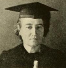 A middle-aged white woman wearing academic robes and a mortarboard cap