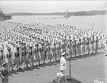 Black and white photo of men in military uniforms on the deck of an aircraft carrier