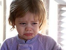 a young child in a pink sweater crying and looking sad