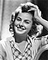 Promotional photograph of Ingrid Bergman for Gaslight. She is looking front, smiling and touching her hair.