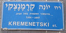 The blue Israeli street sign is in Hebrew. Translated to English it says: "Yonah Kremenetski, one of the first industrialists in Tel Aviv (1850–1936)."