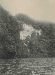 Photo en noir et blanc prise d'un bateau montrant une île escarpée et une falaise à nue.