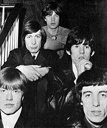 Black-and-white photograph of the Rolling Stones sitting on a staircase in 1965.