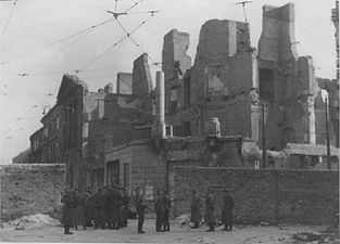 IPN copy #53 (No image caption, in section This is how the former Ghetto looks after having been destroyed) Nalewki Street, looking South at the gate at Nalewki/Gęsia/Franciszkańska intersection. Beyond the wall on the right Posner house at Nalewkach 29.