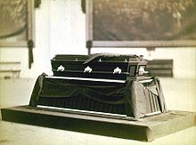 Photographie en noir et blanc d'un cercueil reposant sur un catafalque