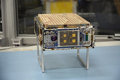 Modèle de cubesat posé sur une table de laboratoire.