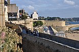 The right image shows the city wall of St Malo, France, as people walk across it.