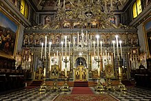 Picture showing the iconostasis of the Church of San Nicolò flanked by candles.