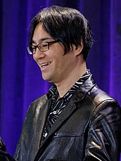 A Japanese man speaking at a podium