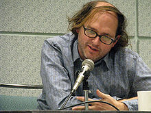 Daniel Waters, seated at a table and speaking into a microphone