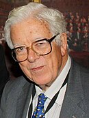 Colour photograph of Geoffrey Howe in grey suit and blue tie