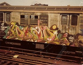 A subway car covered with graffiti can be seen. The image has faint amounts of yellow throughout.