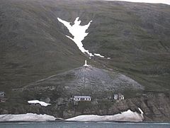 Vue sur le massif montagneux du cap Dejnev (2001). On distingue des vestiges d'installations (période soviétique) et le monument (forme de phare) érigé en l'honneur de Simon Dejnev au sommet d'un promontoire.