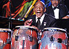 A man wearing a tuxedo is playing the congas