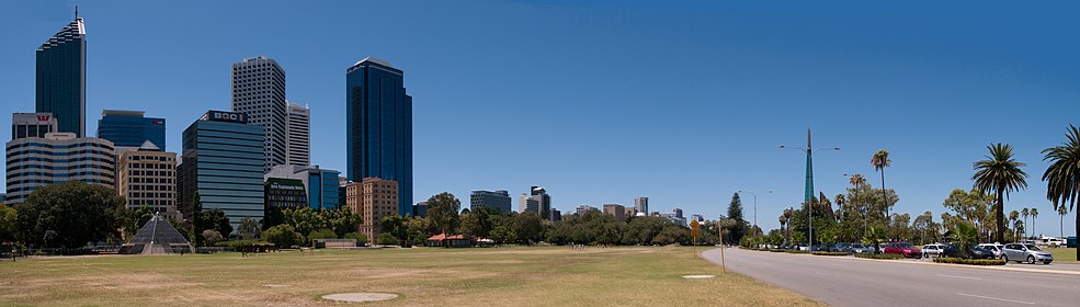 Tall buildings of Perth CBD on the left, grass parkland in the centre, road and foreshore to the right, with bell tower in background