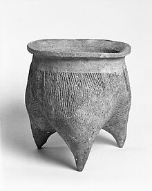 A stout tripod ceramic cooking vessel, in a museum