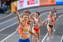 Photo of Femke Bol holding one hand in the air while finishing ahead of the other competitors