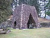 A large stone iron furnace with openings on each of the two sides visible