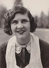 Photographie d'une jeune femme aux cheveux ondulés ramenés sur le côté et portant un foulard en dentelle