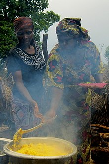 deux femmes malaxant un plat en cuisson