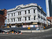 A white, three storey building surrounded by construction hoardings