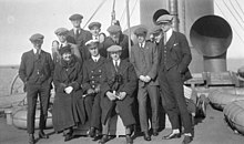 Group photo of team dressed in suits on the deck of an ocean liner