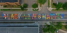 The phrase "Black Lives Matter" is displayed on a road. Inside each letter is a different artistic design.