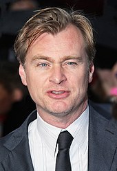 Christopher Nolan is looking directly towards the camera.