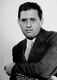 head shot of a well-dressed man wearing glasses