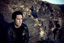 A man sitting in front of a field of craggy rocks.