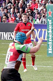 Ronan O'Gara standing in the field with Munster, near a Heineken-sponsored post pad, in 2013