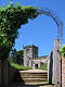 Part of a battlemented church and tower seen through an archway