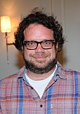A bearded, smiling, bespectacled Christophe Beck in a plaid shirt