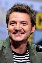 Pedro Pascal facing the to the left next to a microphone