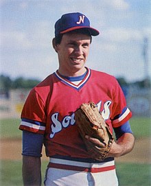 A man in a red baseball jersey, white pants, and blue cap