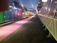 colourful rainbow fencing and bus shelters on Grafton Bridge lit at night