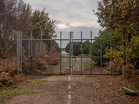 A large metal gate surrounded by woodland