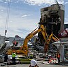 Diggers working in building rubble in front of a burned lift shaft