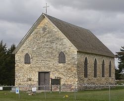 Stone building, four windows along side, small window on either side of front door