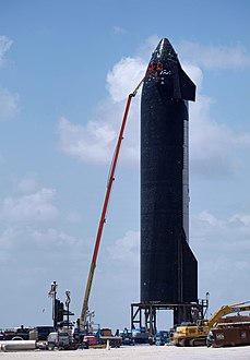 Photograph of a worker repairing a spacecraft's black heatshield