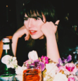 Emily Warren sitting at a table with flowers, resting her head on her hands.
