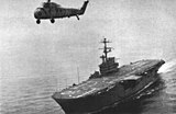 USS Tripoli during trials in the Gulf of Mexico, accompanied by a Sikorsky H-34 helicopter.