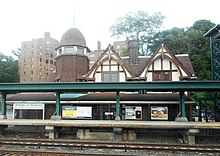 A view of an ornate structure with railroad tracks and a modern elevated platform and metallic structure in the foreground