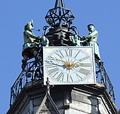 Vue en contre plongée, d'une horloge au sommet d'un campanile, avec deux statues de chaque côté