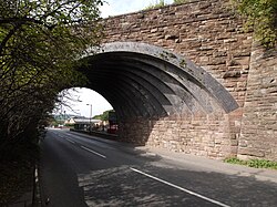 A stone arch spanning a narrow road at an oblique angle