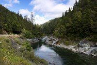 Narrow river between forests and next to a road